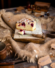 homemade tasty biscuit cake with cherries, almond flakes, powdered sugar on top