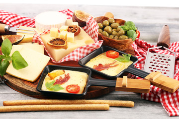 Delicious traditional Swiss melted raclette cheese on diced boiled or baked potato and baguette served in individual skillets with salami..