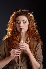 Portrait of young red haired caucasian woman with reed-pipe