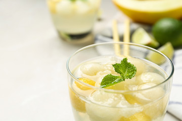 Glass of melon ball cocktail with mint on table, closeup