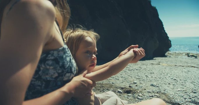 Young mother applying sun lotion to her toddler's body on the beach