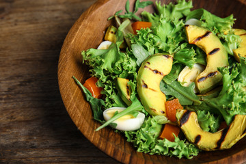 Delicious avocado salad with boiled eggs in bowl on wooden table, closeup