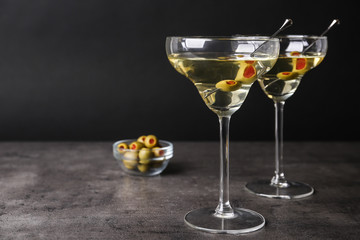 Glasses of Classic Dry Martini with olives on grey table against black background. Space for text