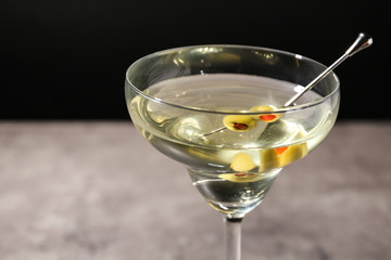 Glass of Classic Dry Martini with olives on table against black background, closeup