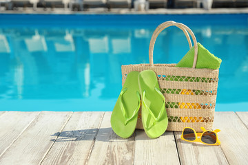 Beach accessories on wooden deck near outdoor swimming pool, space for text