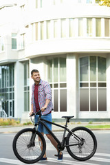 Fototapeta na wymiar Handsome man with modern bicycle on city street