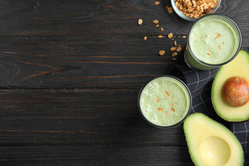 Glasses of tasty smoothie with avocado and oatmeal on black wooden table, flat lay. Space for text