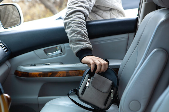 a young man steals a bag from a car through a window