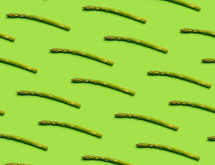 Pattern with fresh asparagus on green table background.