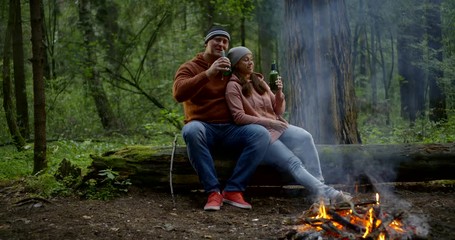 happy married couple are drinking beer and enjoying seclusion and silence in forest