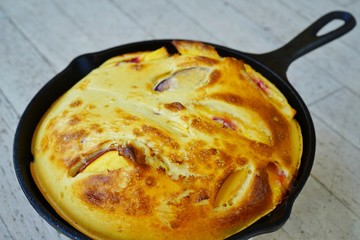 A peach Baby Dutch pancake clafoutis in a cast iron pan
