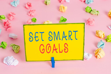 Word writing text Set Smart Goals. Business photo showcasing giving criteria to guide in the setting of objectives Colored crumpled papers empty reminder pink floor background clothespin