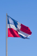 Flag of Dominican Republic (DR) waving in the wind with blue sky on background