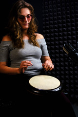 Playing on ethnic African percussion instrument, horizontal photo. A young woman plays a drum...