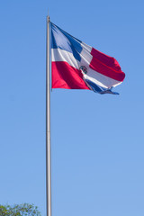 Flag of Dominican Republic (DR) waving in the wind with blue sky on background