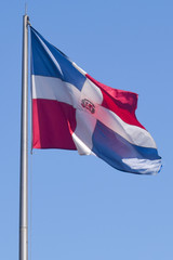 Flag of Dominican Republic (DR) waving in the wind with blue sky on background