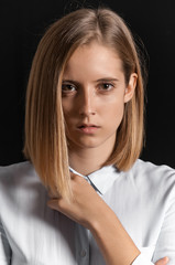 Blonde girl photographed in studio with black background.