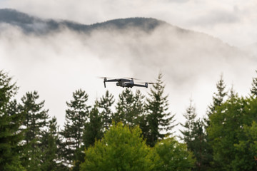 Drone with camera flying over mountain fields.