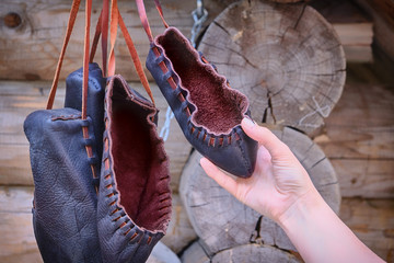 Woman holding a retro Shoe made of rough leather. The shoes are vintage style from primitive material.