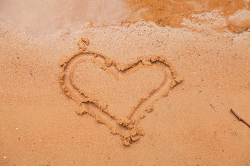 Heart drawn in the sand. Beach background. Top view