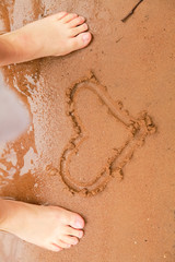 Heart drawn in the sand. Beach background. Top view