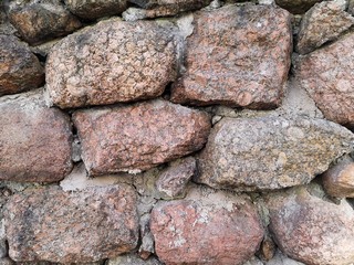 A fragment of a historic medieval fortress wall made of natural stone. Background