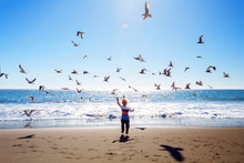 Happy and free boy on the beach with seagulls