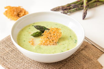 Homemade green asparagus soup served with parmesan chips