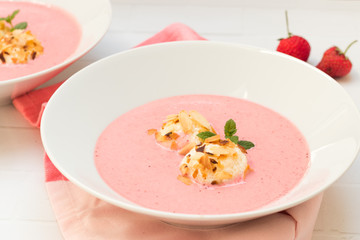 Cold strawberry soup in white bowl with almond covered cottage cheese balls
