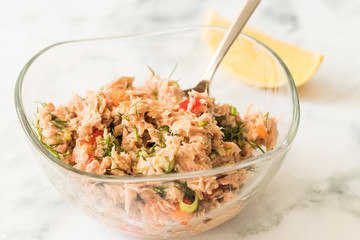 Preparing tuna salad in glass bowl with a slice of lime on kitchen table