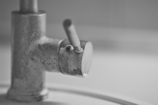 handle of an old chrome faucet in lime, black and white photo