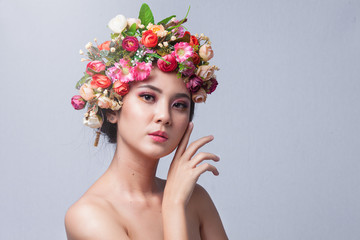 Portrait of beautiful young asian woman with flowers. Brunette woman with luxury makeup. Perfect skin. Eyelashes. Cosmetic eyeshadow. Perfect Creative Make up and Hair Style.