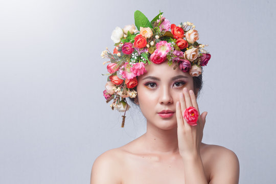 Portrait of beautiful young asian woman with flowers. Brunette woman with luxury makeup. Perfect skin. Eyelashes. Cosmetic eyeshadow. Perfect Creative Make up and Hair Style.