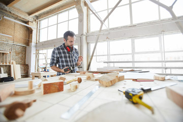 Wide angle portrait of mature carpenter working with wood in modern workshop, copy space