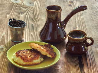 cup of coffee with cezve and homemade cheesecakes on a wooden table