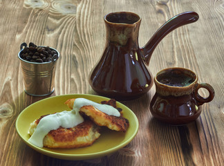 cup of coffee with cezve and homemade cheesecakes on a wooden table