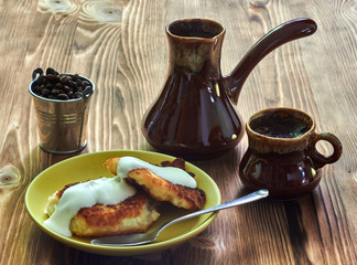 cup of coffee with cezve and homemade cheesecakes on a wooden table
