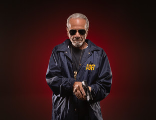 Special agent with gun in his hand, looking calm and ready to talk to the fugitive.