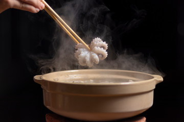 Hand holding chopsticks with squid over hot pot, Thai style, Barbecue Buffet with smoke