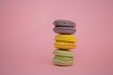 Stack of three macarons on a pink background