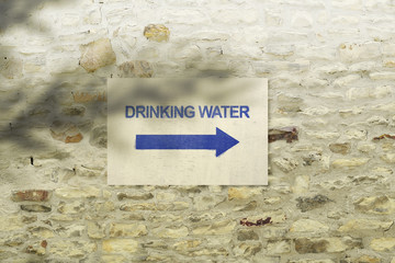 Pointer with the words "Drinking Water" and an arrow on a carelessly folded stone wall