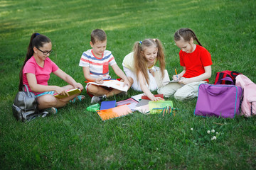 Four children sitting on the green grass.