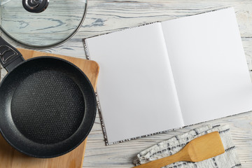 Blank cookbook for your tex, composition with frying pan on wooden table