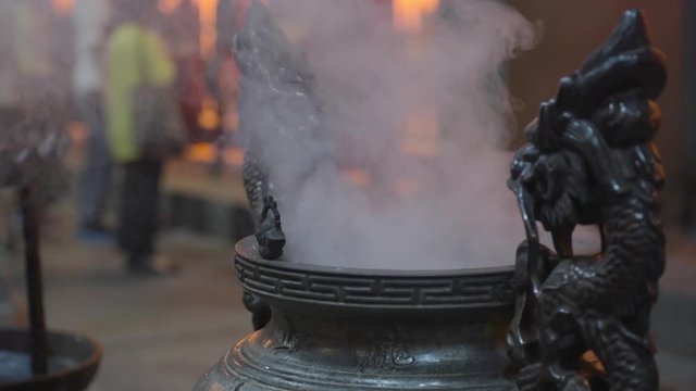 Smouldering incense pot in Longshan Temple with people in background. Static real time.