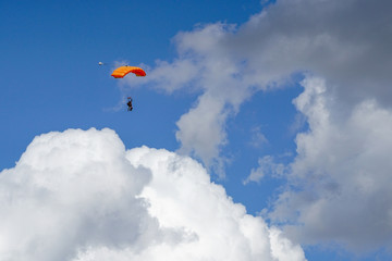 Fototapeta na wymiar colored parachute jumper tandem on a blue sky over clouds