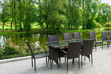 Obraz premium empty restaurant with brown chairs by the beautiful pond in summer