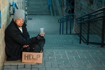 A man, homeless, a person asks for alms on the street with a Help sign. Concept of homeless person,...