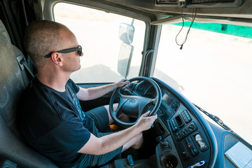 Truck driver with sunglasses working hard in a sunny day