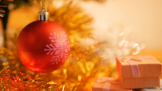 Cloes up red Christmas ball and blinker light with gift box on the table.