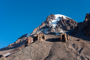 Mount Kazbek, rocky peak covered by snow at sunny day. Mountains landscape. Caucasus, Georgia. Hiking, mountaineering, extreme sport concept. Copy space
